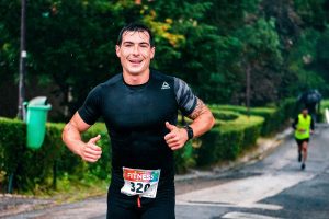 Man smiling while running outdoors in a race, demonstrating how exercise can help manage panic and anxiety.
