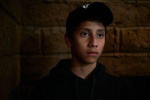 Young person sitting alone looking contemplative, representing teens facing language barriers in mental health care.