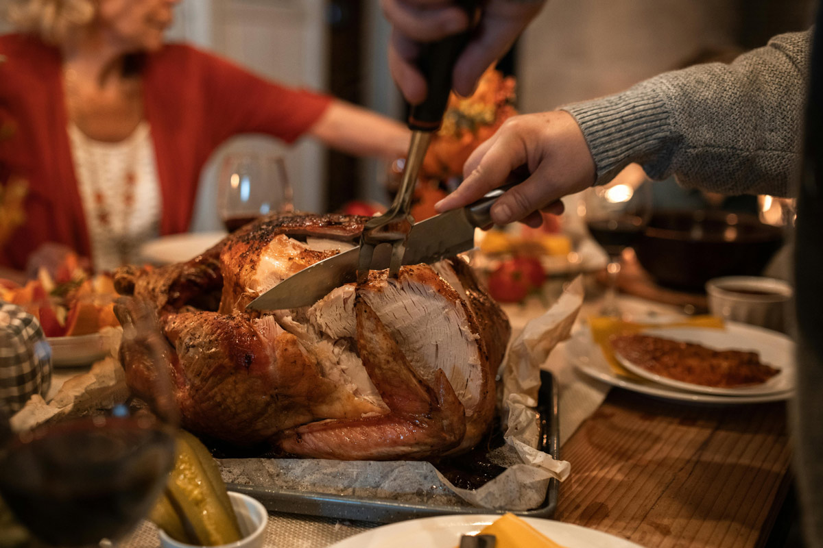 Person carving turkey for a family gathering.