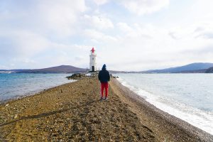 Person on a beach facing a lighthouse, symbolizing guidance and hope in the storm of anxiety.