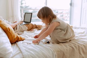 Mother and young daughter sitting together on bed having a caring conversation, representing inner child healing and nurturing relationships.