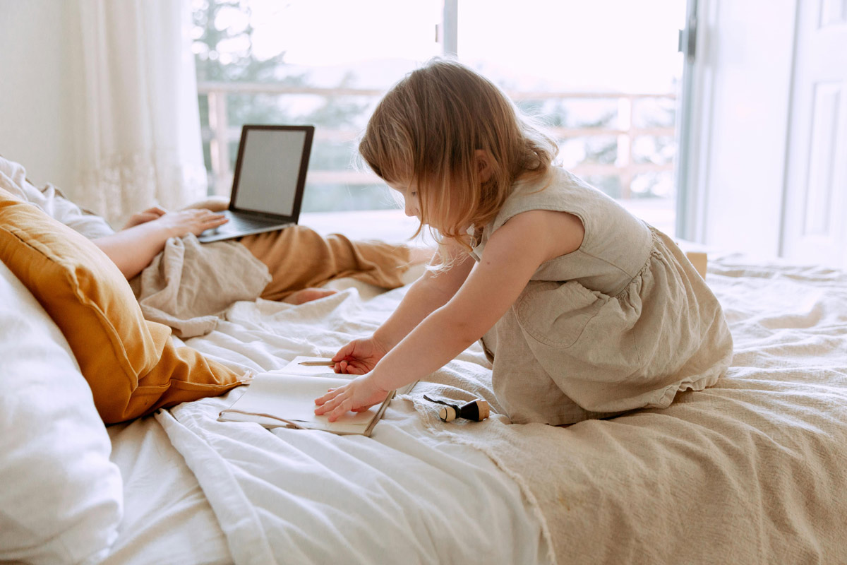 Mother and young daughter sitting together on bed having a caring conversation, representing inner child healing and nurturing relationships.