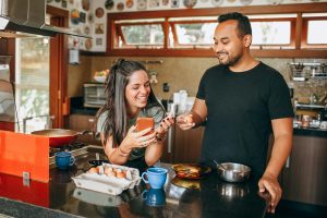 Smiling couple cooking together in kitchen, demonstrating how daily routines help maintain love in relationships.