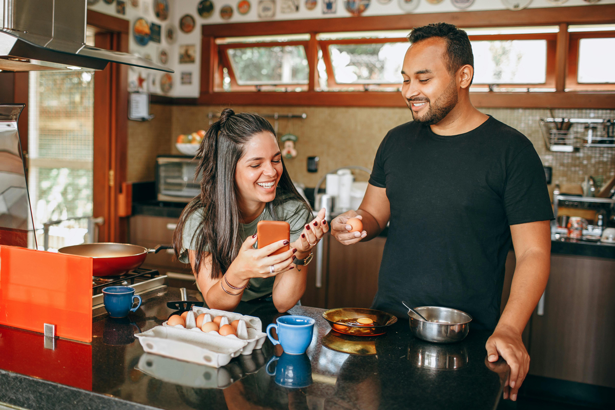 Smiling couple cooking together in kitchen, demonstrating how daily routines help maintain love in relationships.
