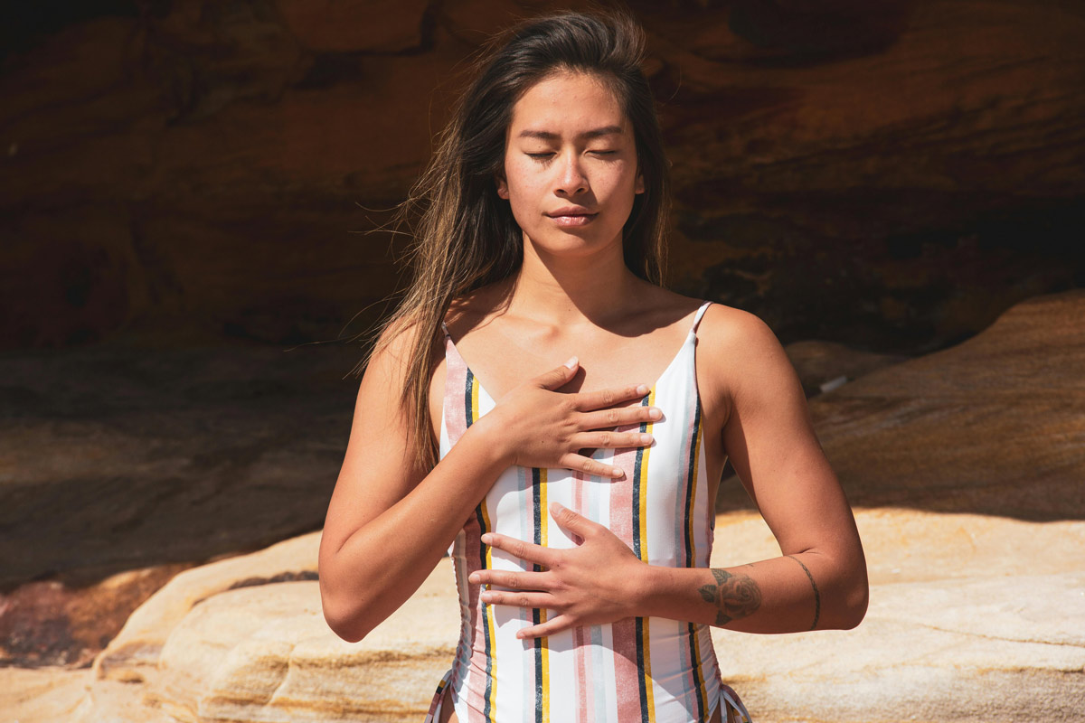 Young woman with eyes closed and hands on chest, practicing emotional awareness and mindful breathing.