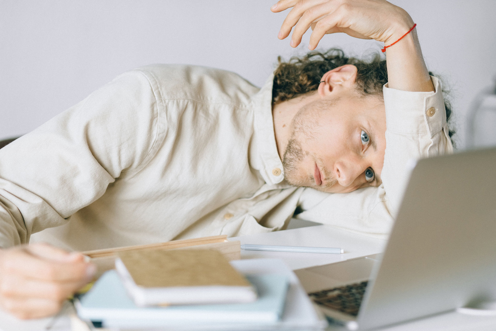 Stressed man resting his head on his desk next to a laptop, showing signs of burnout and anxiety from career uncertainty.