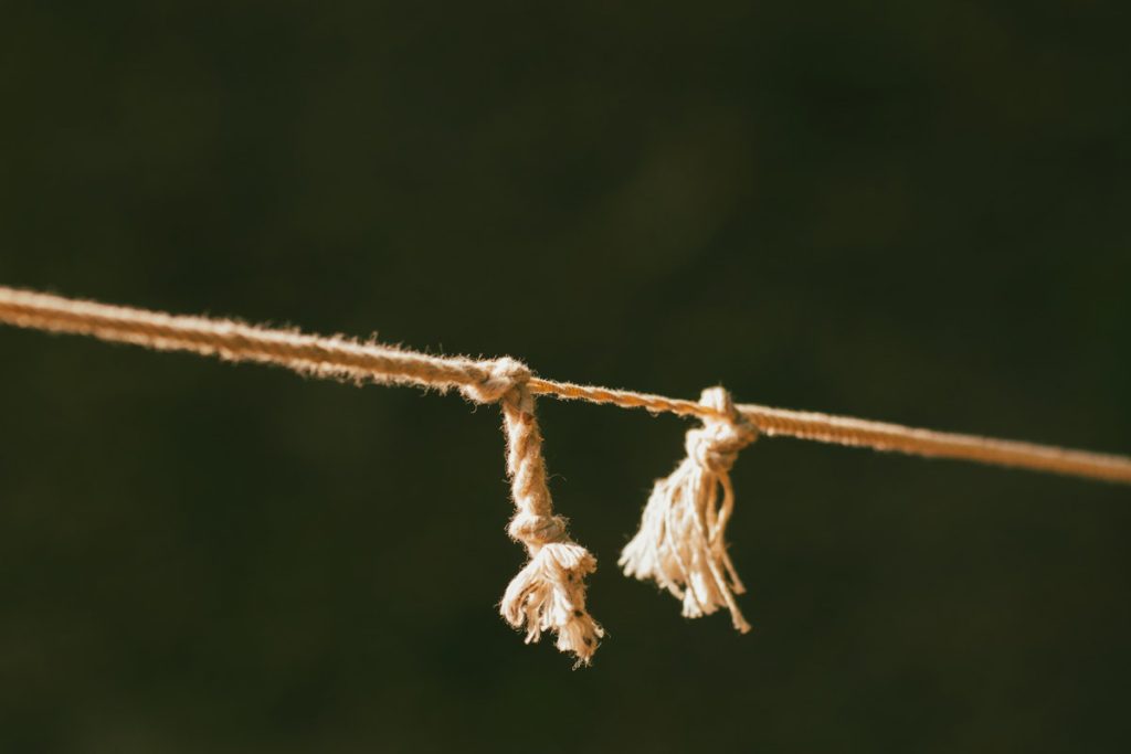 Frayed rope splitting into two separate ends in warm sunlight, symbolizing breaking free from a trauma bond.