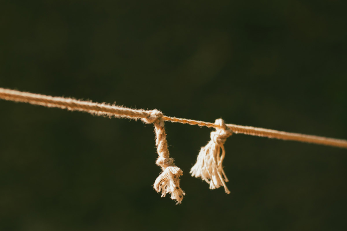 Frayed rope splitting into two separate ends in warm sunlight, symbolizing breaking free from a trauma bond.