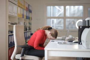 Woman looking exhausted while working on a laptop, illustrating burnout that can feel like depression.