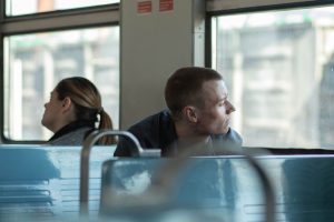 Young man on a train gazing thoughtfully out the window, reflecting on his identity in recovery.