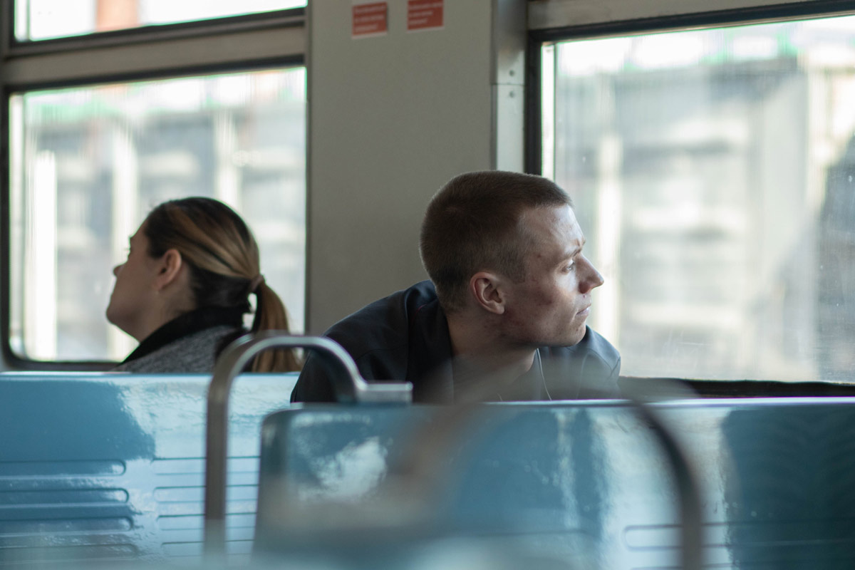 Young man on a train gazing thoughtfully out the window, reflecting on his identity in recovery.
